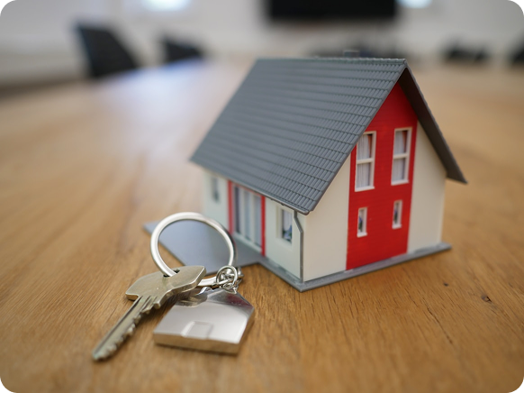 Small house model with keys beside it representing buying a new home and property ownership.