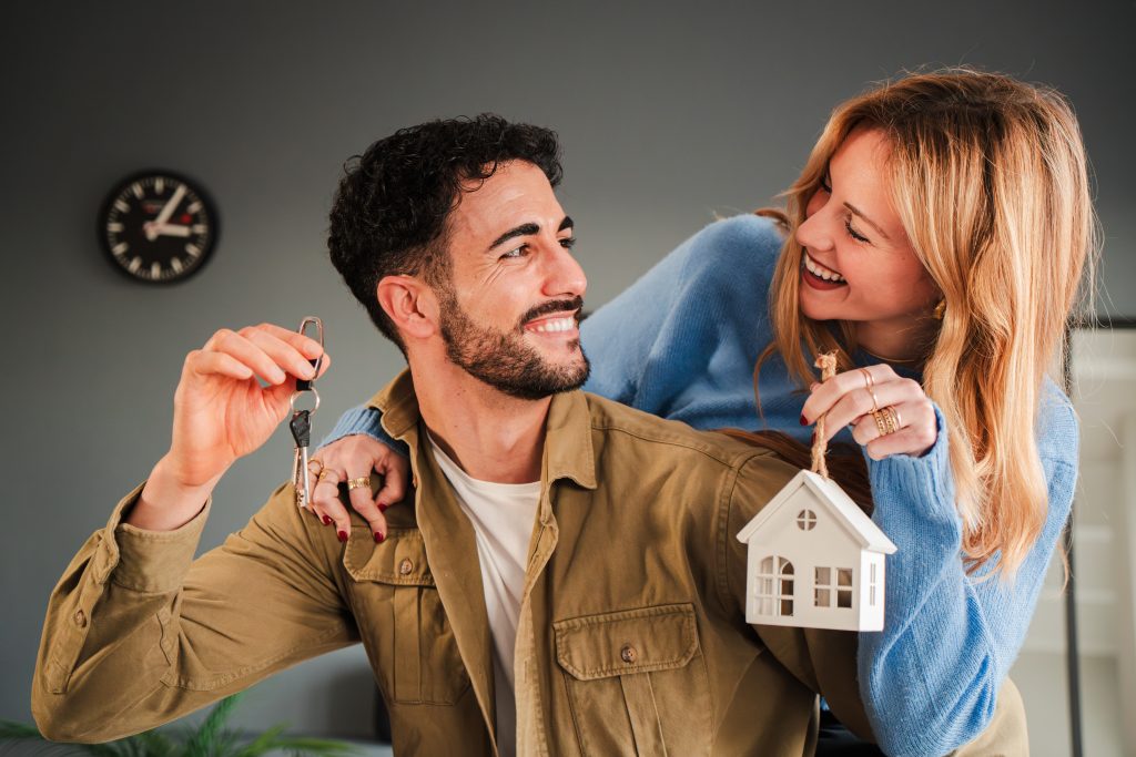 Husband and wife hugging in their apartment, excited about moving into their new home.